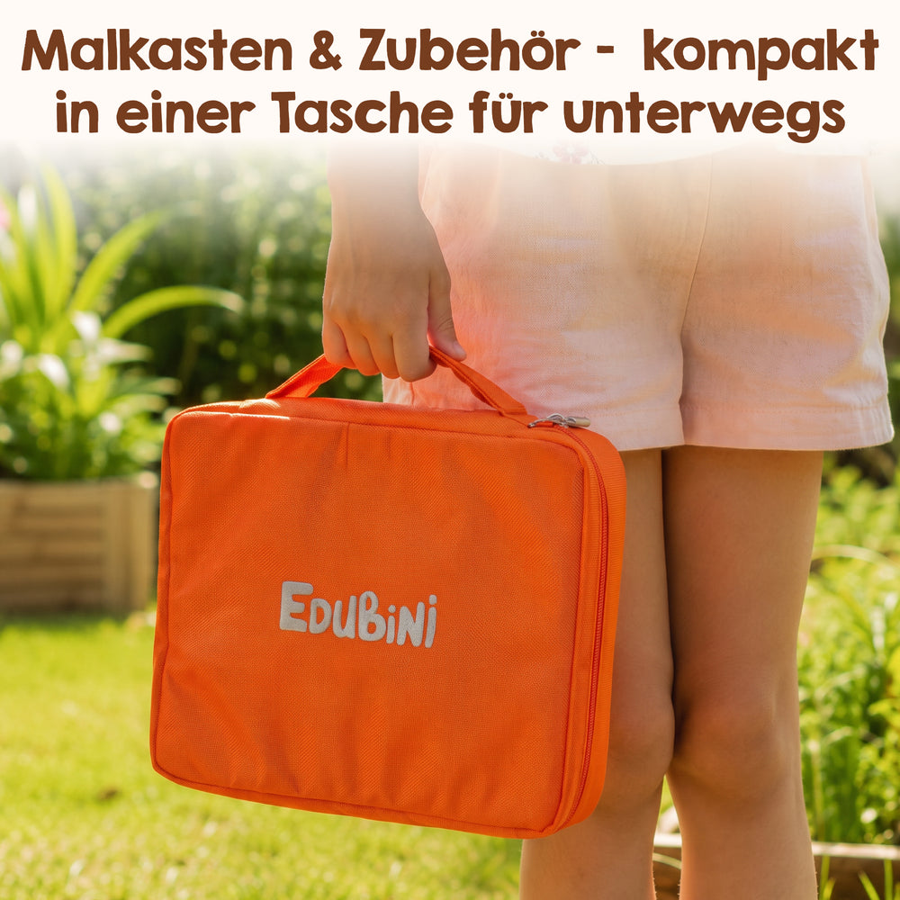 Eine Person hält im Freien die orangefarbene „Edubini Premiumtasche für Zauber-Malkasten“ – eine Tasche für Malutensilien – in der Hand. Darüber steht auf Deutsch: „Malkasten & Zubehör – kompakt in einer Tasche für unterwegs“. Der sonnendurchflutete Garten im Hintergrund bildet die perfekte Kulisse für das Malen unterwegs.